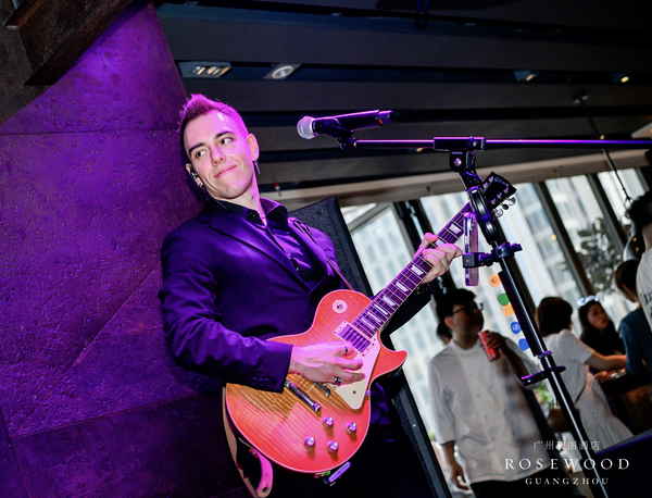 Professional picture of our pop rock singer and guitarist playing instrument while looking to side during indoor performance | Altus Entertainment